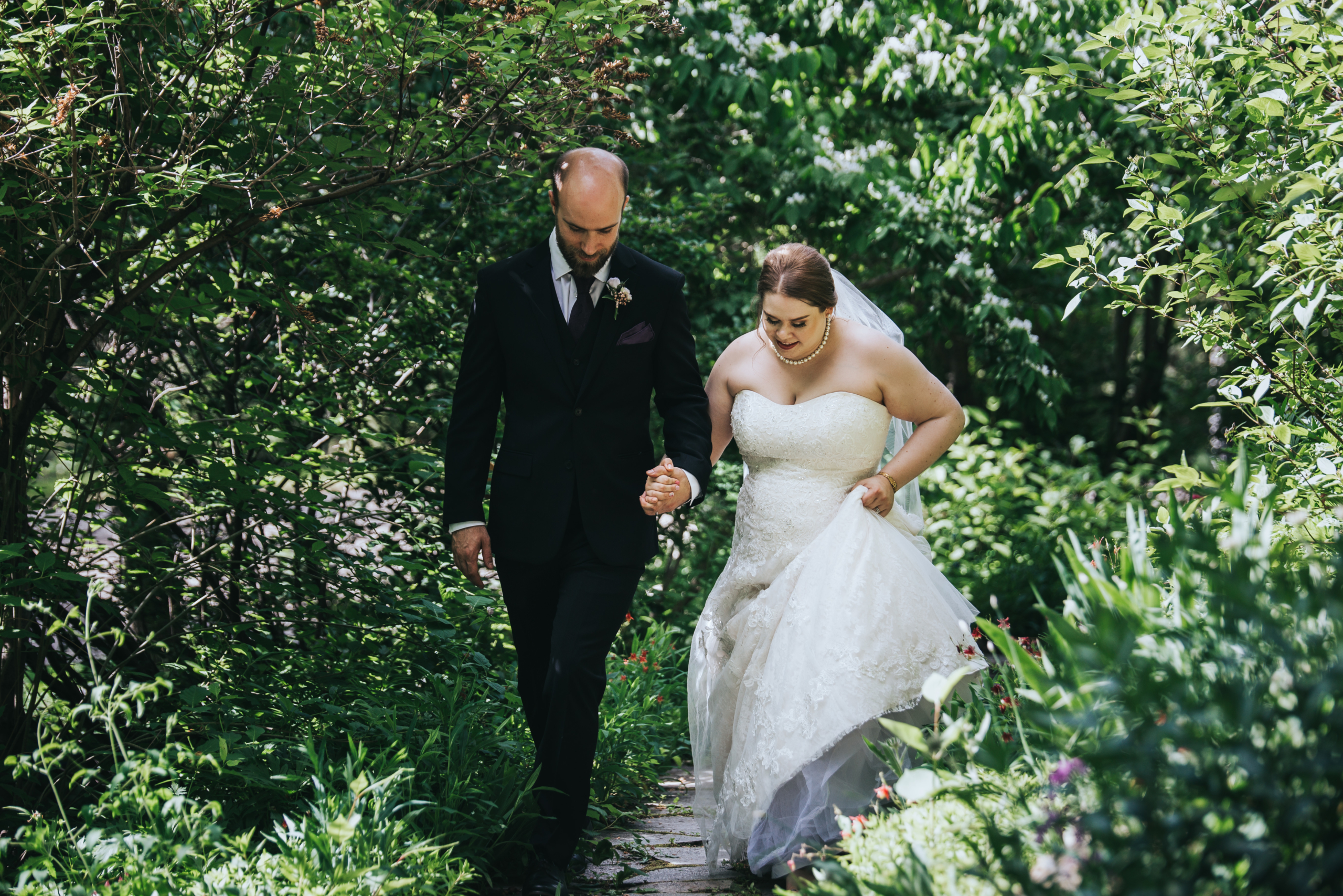 bride and groom walking through garden in calgary