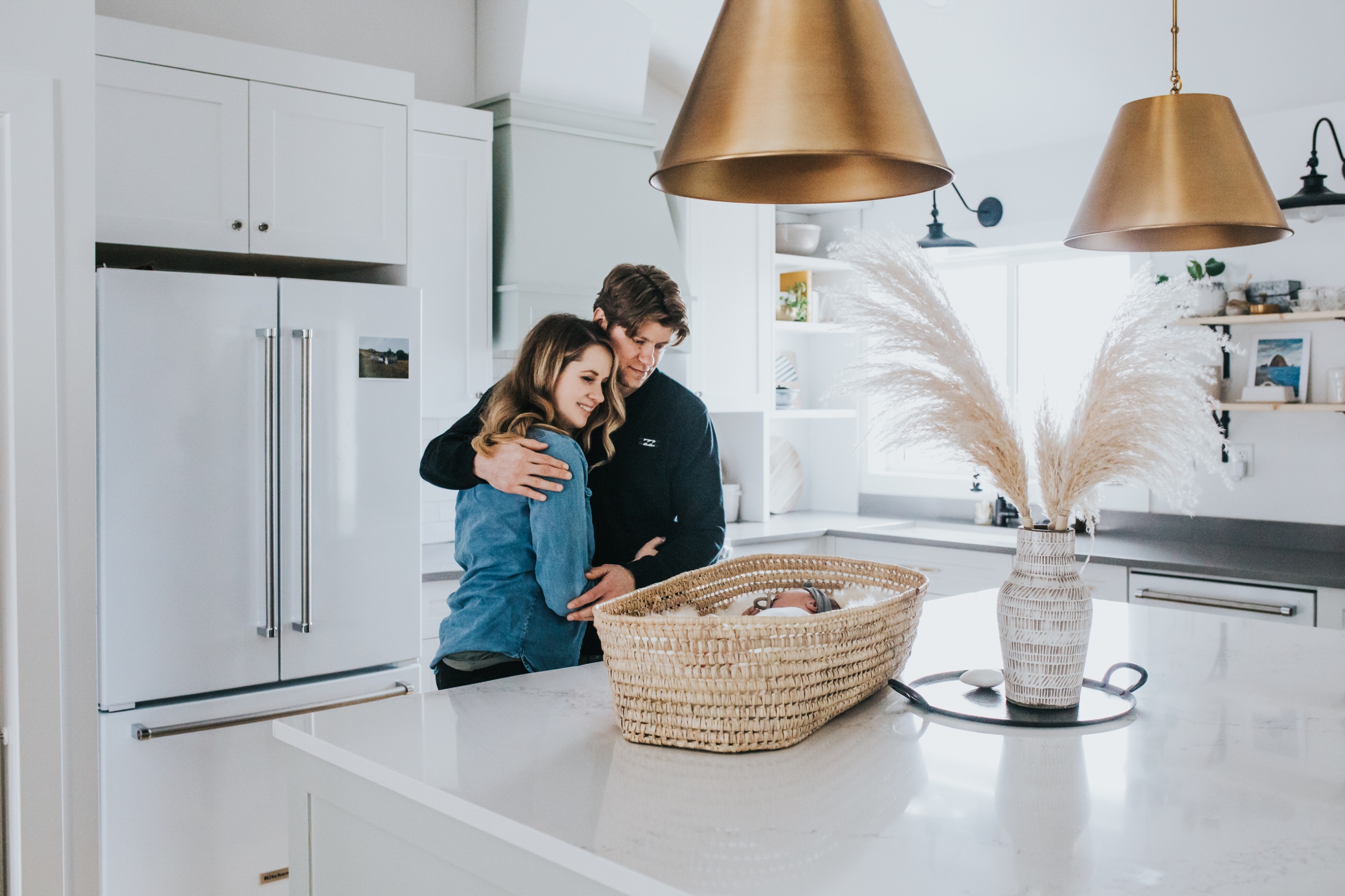 Couple watching newborn baby in bassinet on kitchen counter
