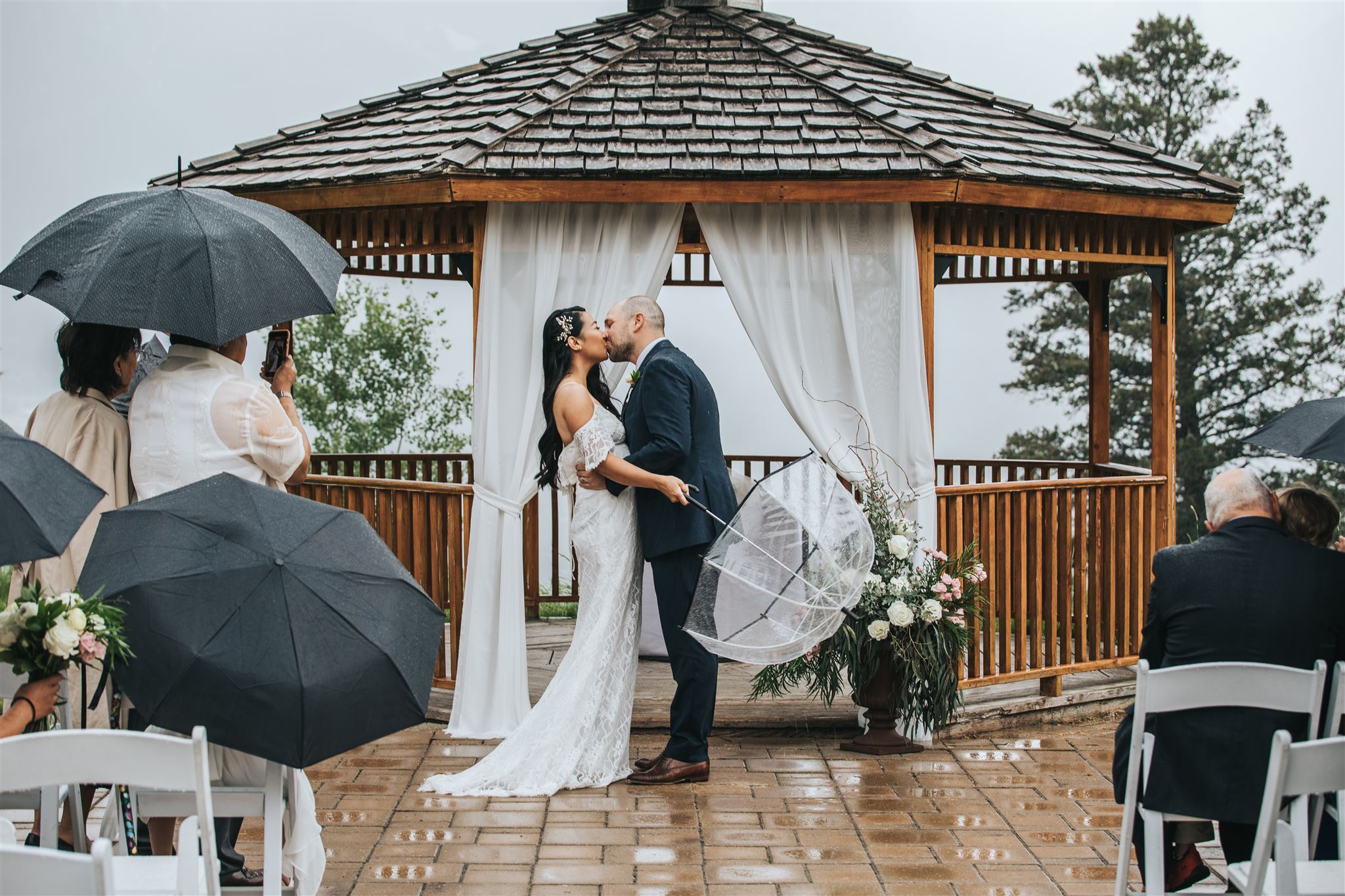 Bride and Groom first kiss during wedding ceremony in the rain at silvertip resort in canmore, alberta