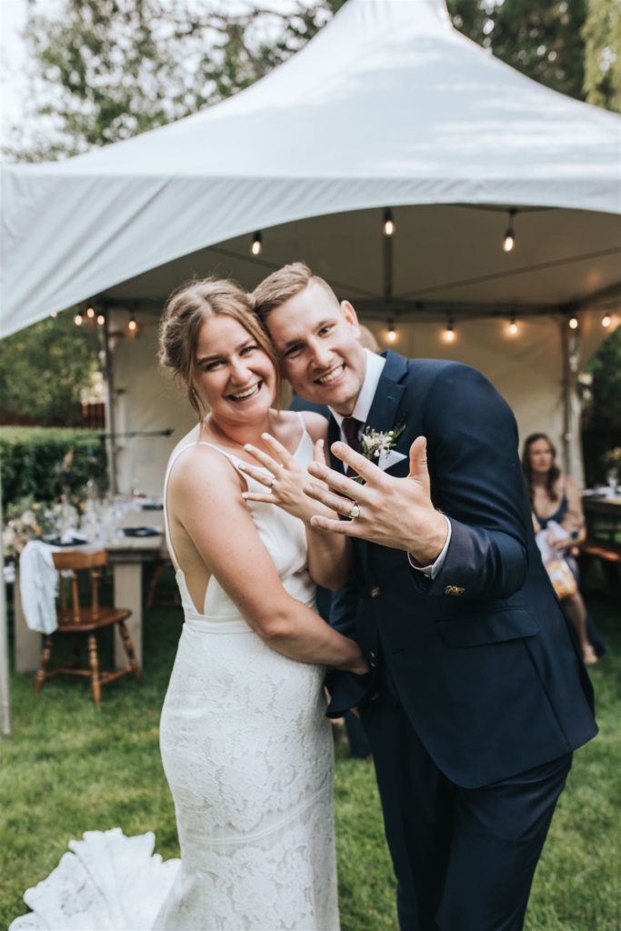 Bride and Groom showing wedding rings in backyard wedding