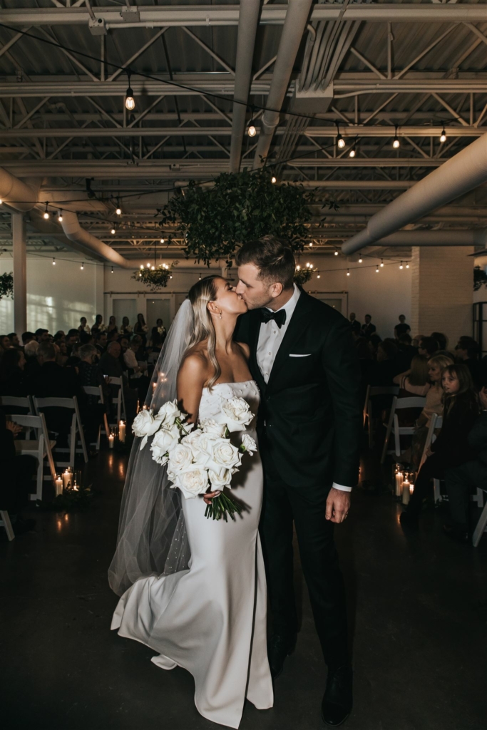 Bride and Groom kissing at the end of the aisle at The Brownstone by Calgary photographer Sue Moodie Photography