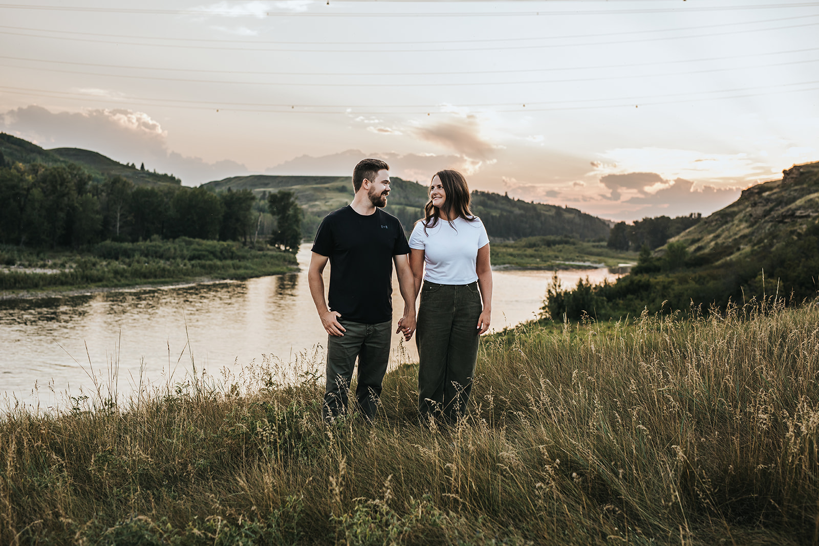 Couple holding hands during engagement photography session overlooking river