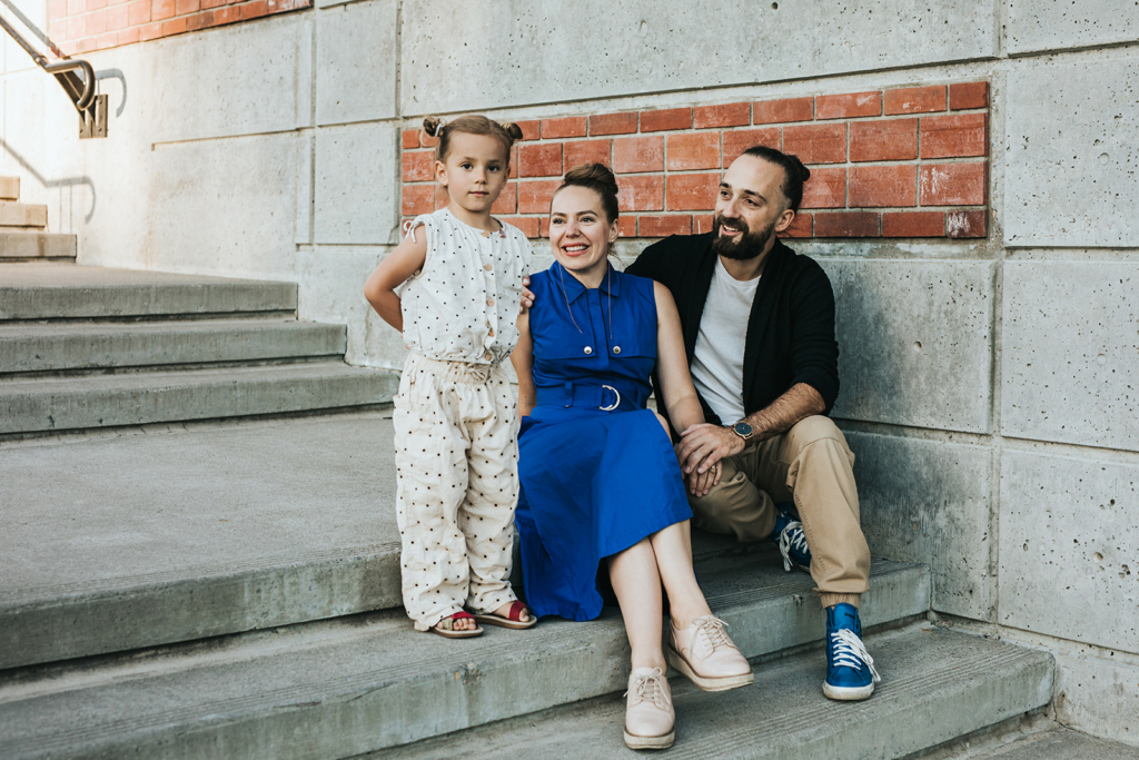Family of three sitting on stairs in Bridgeland Calgary for their family lifestyle photography session