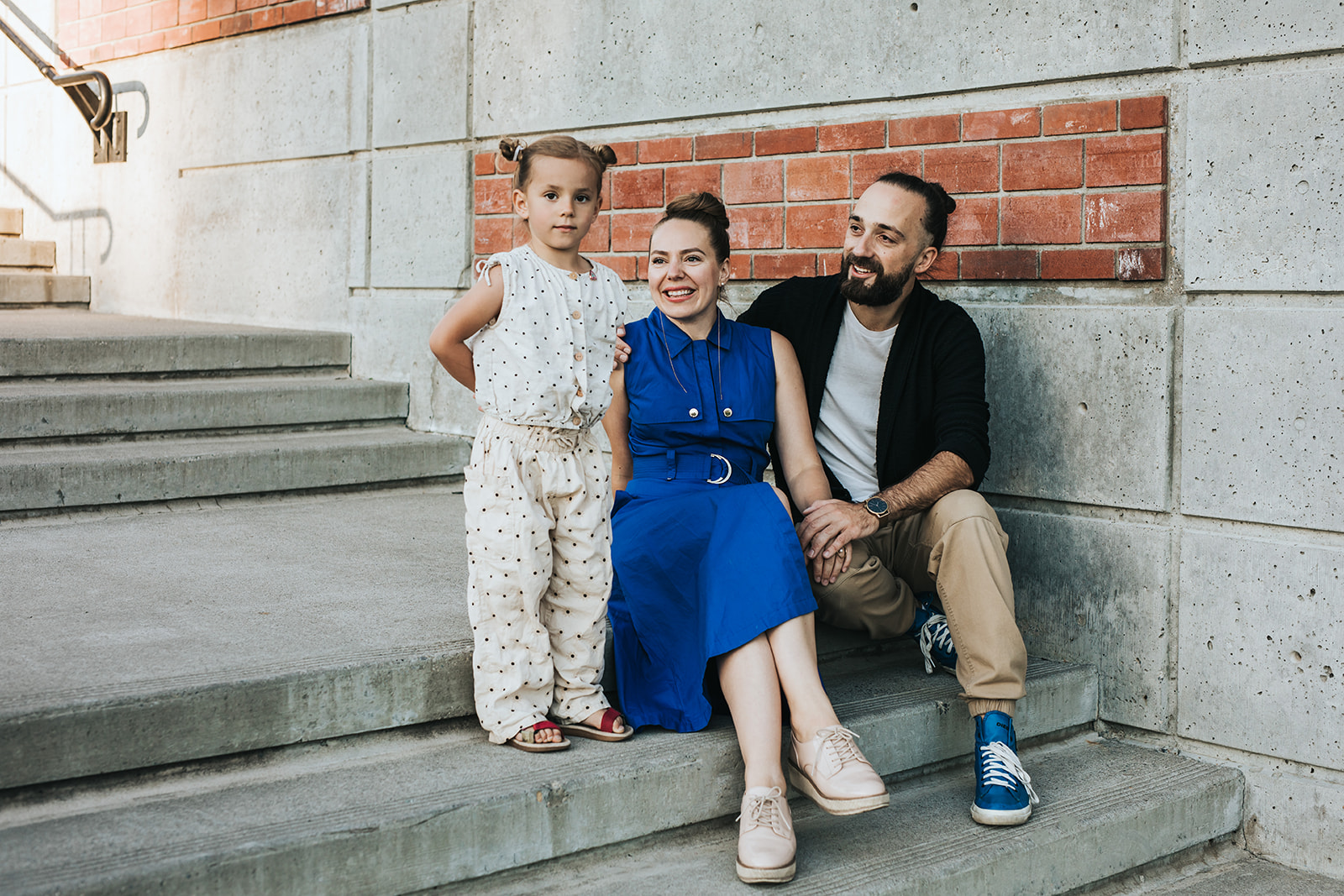 Family of three sitting on stairs in Bridgeland Calgary for their family lifestyle photography session