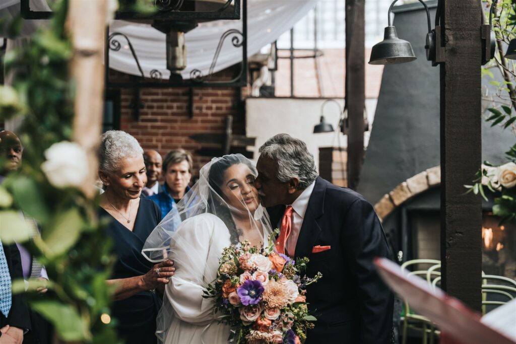 Bride being kissed by Dad during ceremony in the guide- What to look for in a wedding photographer by Calgary Wedding Photographer Sue Moodie Photography