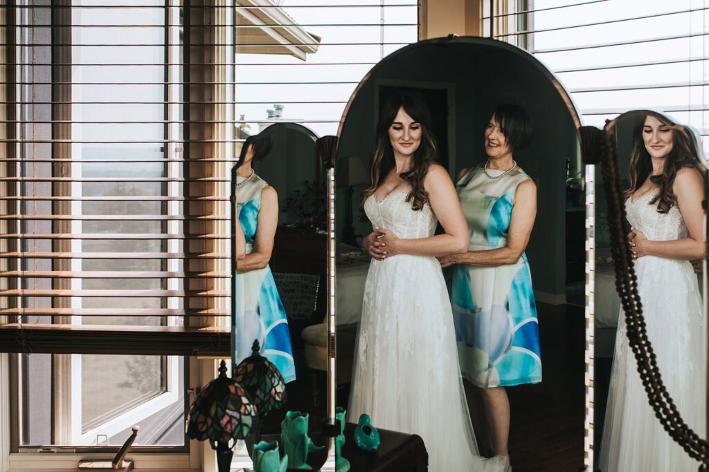 Mother of bride helping her daughter get into her wedding dress on this calgary wedding portfolio